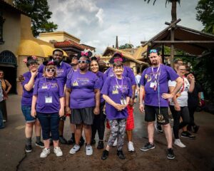 people in matching purple shirts smiling at disney world