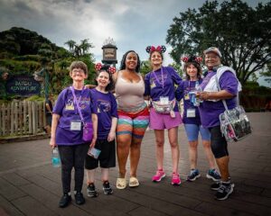 people in matching purple shirts smiling at disney world