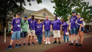 people in matching purple shirts smiling at disney world