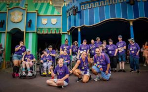 people in matching purple shirts smiling at disney world