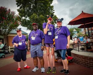 people in matching purple shirts smiling at disney world