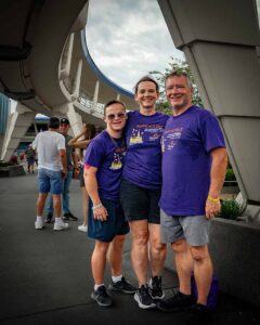 people in matching purple shirts smiling at disney world