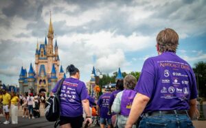 people walking into disney world with castle in background