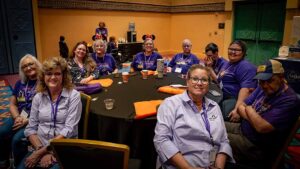 crowd of people in matching purple shirts smiling