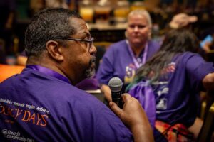 man in purple shirt with microphone